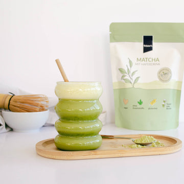 Zubereiteter Matcha mit Haferdrink im glas neben dem Produkt