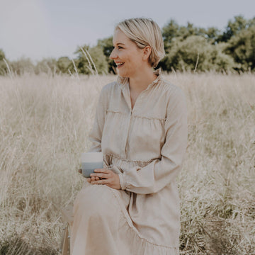 Frau lachend in der Natur mit Pelster's Becher blau in der Hand 